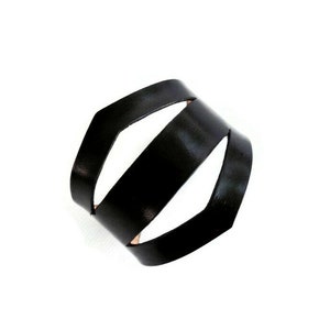 May include: A black leather bracelet with a woven design. The bracelet is made of three strips of leather that are woven together to create a unique and stylish look.