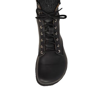 Puede incluir: Bota negra de cuero con cordones, ojales plateados y cordones negros. La bota se lleva con calcetines de punto grises y vaqueros azules. Un estilo cl&aacute;sico, adecuado para varios conjuntos.
