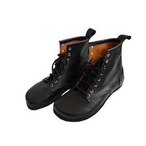 Puede incluir: Un par de botas de cuero negro con dise&ntilde;o de cordones. Las botas tienen punta redondeada y una leng&uuml;eta en la parte trasera. El forro interior es de color marr&oacute;n claro. Las botas se muestran sobre un fondo blanco.