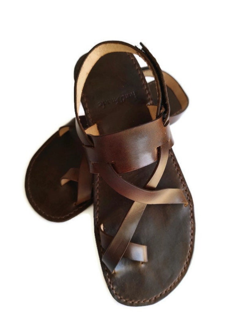 Op de afbeelding: Bruine leren sandalen met gekruiste banden en een gespsluiting.