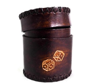 May include: A brown leather dice rolling cup with two dice embossed on the side. The cup is made of genuine leather and has a stitched seam around the top and bottom.
