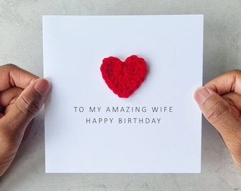 May include: A white card with a red crocheted heart and the text "To my amazing wife Happy Birthday".