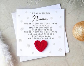 May include: A white greeting card with the text "To a very special Nana" and a red heart. The card includes a poem about the best gift being a wonderful Nana. Silver and gold Christmas decorations are in the background.