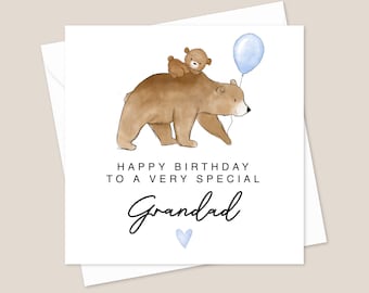 Può includere: Un biglietto di auguri per il compleanno con un orso marrone e un orsetto marrone più piccolo sulla sua schiena. L'orso tiene un palloncino blu. Il biglietto dice "Buon compleanno a un nonno molto speciale" con un cuore blu.