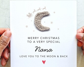 May include: A white Christmas card with the text "MERRY CHRISTMAS TO A VERY SPECIAL Nana LOVE YOU TO THE MOON & BACK". The card features a crocheted crescent moon, a Santa sleigh, reindeer, stars, and a red heart.
