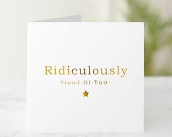 May include: White card with gold foil lettering that reads "Ridiculously Proud Of You!" with a gold star below the text.