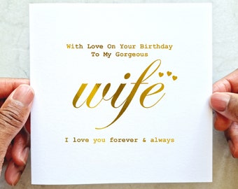 May include: A white greeting card with gold foil text. The card reads "With Love On Your Birthday To My Gorgeous wife I love you forever & always." The word "wife" is in a stylish script font.