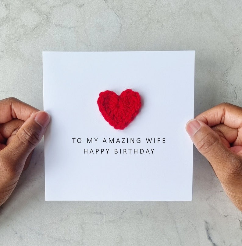 May include: A white card with a red crocheted heart and the text "To my amazing wife Happy Birthday".