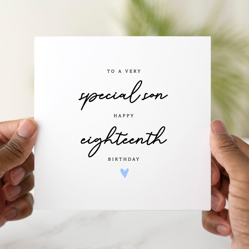 May include: A white card with black text that reads 'To a very special son Happy eighteenth Birthday' with a light blue heart below the text.
