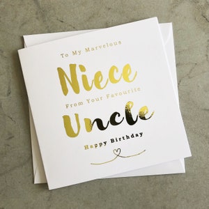 Può includere: Un biglietto bianco con lettere dorate che recitano "To My Marvelous Niece From Your Favourite Uncle Happy Birthday".