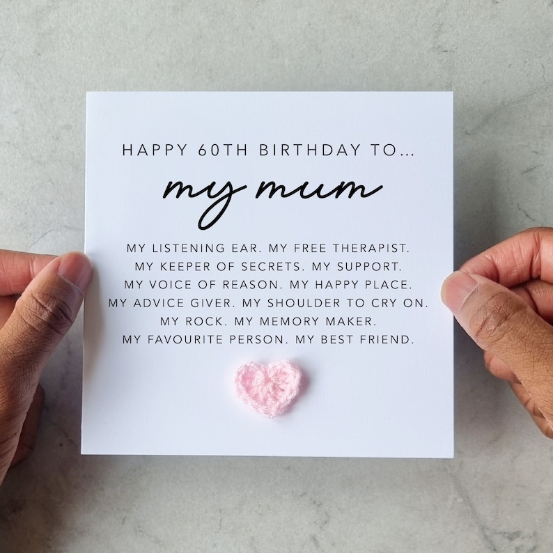 May include: A white card with the text "Happy 60th Birthday to... my mum" and a list of reasons why a mum is special. A pink crocheted heart is attached to the card.