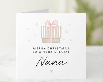 May include: A white Christmas card with a watercolor illustration of two stacked gift boxes tied with a pink bow. The card reads "MERRY CHRISTMAS TO A VERY SPECIAL Nana" with a small pink heart.