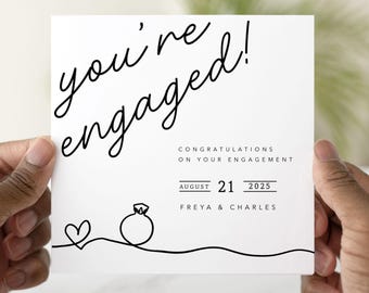 May include: A white engagement announcement card with black script that reads "you're engaged!". The card includes the date August 21, 2025, and the names Freya & Charles, along with a line drawing of a heart and engagement ring.