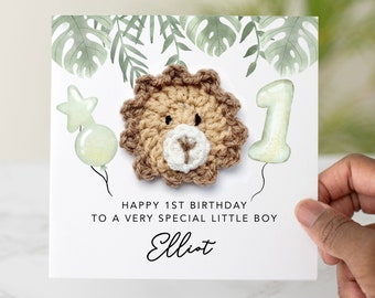 Może przedstawiać: Biała kartka z zielonym listowiem i haftowaną głową lwa. Na kartce napisano "Happy 1st Birthday to a very special little boy Elliot".