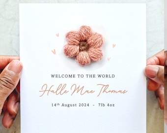 Könnte beinhalten: Eine weiße Karte mit einer rosa gehäkelten Blume und dem Text "Willkommen auf der Welt Halle Mae Thomas 14. August 2024 - 7lb 4oz"
