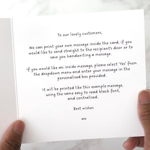 May include: An open white greeting card with black text. The text includes a message to customers about printing a personalized message inside the card. The card is held by a person's hand.
