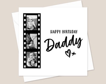 May include: Black and white photo card with a film strip border. The film strip contains three photos of a baby and a father. The card says "Happy Birthday Daddy" with a heart and plus sign.