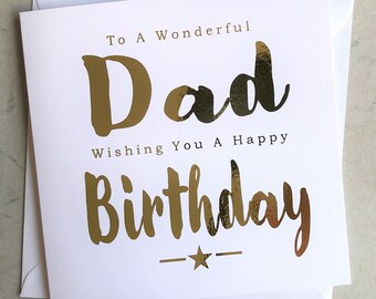 May include: A white birthday card with gold foil lettering that reads "To A Wonderful Dad Wishing You A Happy Birthday." The card includes a gold star and is accompanied by a white envelope.