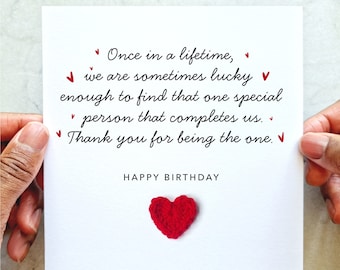 May include: A white card with a handwritten message that reads "Once in a lifetime, we are sometimes lucky enough to find that one special person that completes us. Thank you for being the one. Happy Birthday." A red crocheted heart is attached to the card.