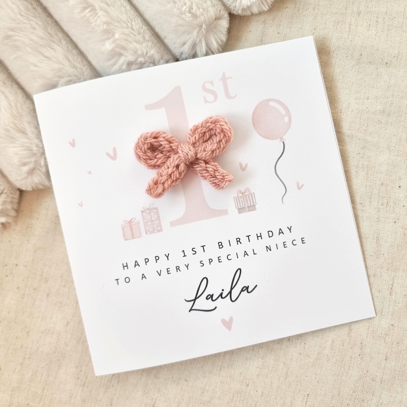 Może przedstawiać: R&oacute;żowa i biała kartka urodzinowa z r&oacute;żową dzianą kokardką, r&oacute;żowym balonem i tekstem "Happy 1st Birthday to a very special niece Laila".