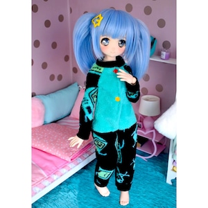 May include: A blue doll with blue hair wearing a turquoise and black patterned pajama set. The doll is standing in front of a pink and white bed.