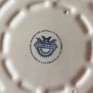 May include: A white ceramic plate with a blue and white logo that reads "ANCIENNE MANUFACTURE IMPERIALE ET ROYALE FONDEE EN 1767 VILLEROY & BOCH SEPTEONTAINES MADE IN LUXEMBOURG. 19", indicating the origin and maker of the plate.