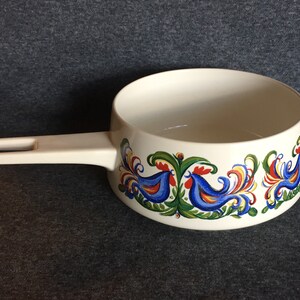 May include: White ceramic saucepan with a white handle and a blue, red, yellow, and green rooster design around the rim.