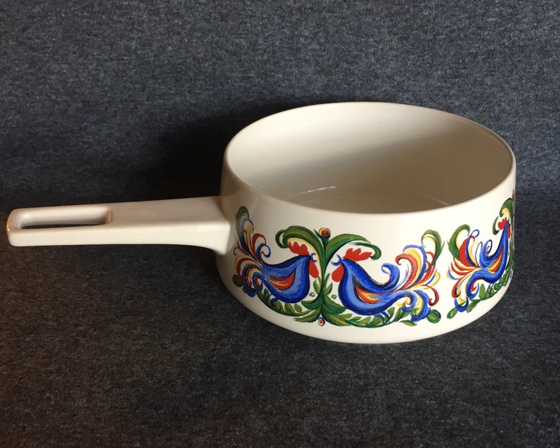 May include: White ceramic saucepan with a white handle and a blue, red, yellow, and green rooster design around the rim.