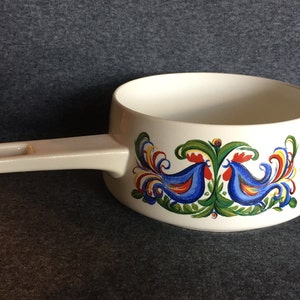 May include: White ceramic saucepan with a white handle and a blue, red, green, and yellow rooster design around the rim.