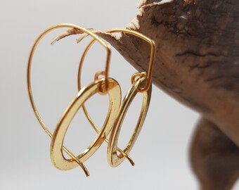 May include: A pair of gold hoop earrings with a simple oval shape. The earrings are made of a hammered metal, giving them a textured look.