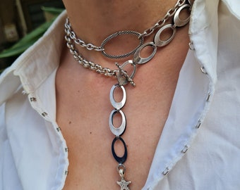 May include: A silver chain necklace with a silver pendant featuring a series of oval links and a star charm.