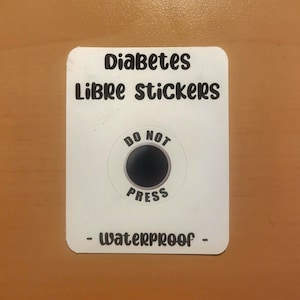 May include: White sticker with black text that reads "Diabetes Libre Stickers" and a black circle with white text that reads "Do Not Press". The sticker also says "Waterproof" in black text.