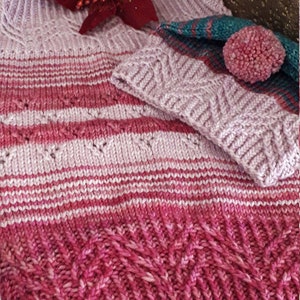 Può includere: Un maglione a righe rosa e rosso lavorato a maglia con un cappello lavorato a maglia rosa abbinato con un pon pon.