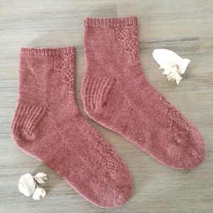 May include: A pair of knitted socks in a deep red color with a textured pattern. The socks are ankle-length and have a ribbed cuff.