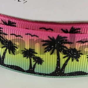 May include: A pink, green, and yellow ribbon with a black silhouette of palm trees and a gradient background. The ribbon has a textured, woven look.