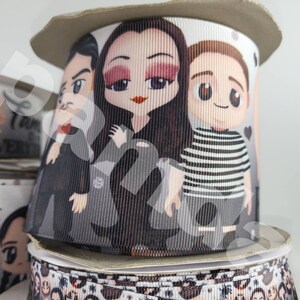 Può includere: Un nastro bianco con una stampa in bianco e nero dei personaggi della famiglia Addams. I personaggi sono in stile cartone animato e sorridono. Il nastro è su un rotolo.