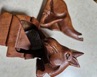 May include: A wooden puzzle box with three separate pieces that fit together. The box is made of dark brown wood and has a carved animal design. The box is open and the inside is visible.