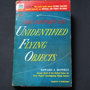 May include: A blue book with the title "The Report on Unidentified Flying Objects" by Edward J. Ruppelt, former head of the United States Air Force Project Investigating Flying Saucers. The book is complete and unabridged.