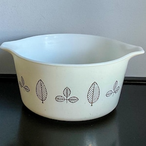 May include: White mixing bowl with a black leaf design. The bowl has a handle on each side.