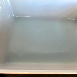 May include: A rectangular, off-white baking dish with slightly curved sides and a glossy finish. The dish has a simple, classic design, suitable for various culinary uses. The interior appears clean and ready for use.