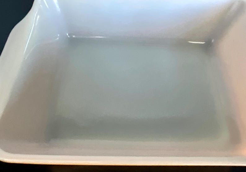 May include: A rectangular, off-white baking dish with slightly curved sides and a glossy finish. The dish has a simple, classic design, suitable for various culinary uses. The interior appears clean and ready for use.