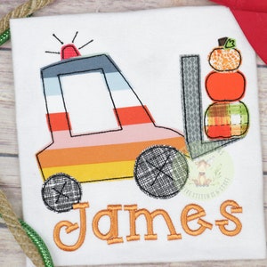 May include: A white onesie with a colorful embroidered forklift and a stack of pumpkins. The name "James" is embroidered below the forklift.