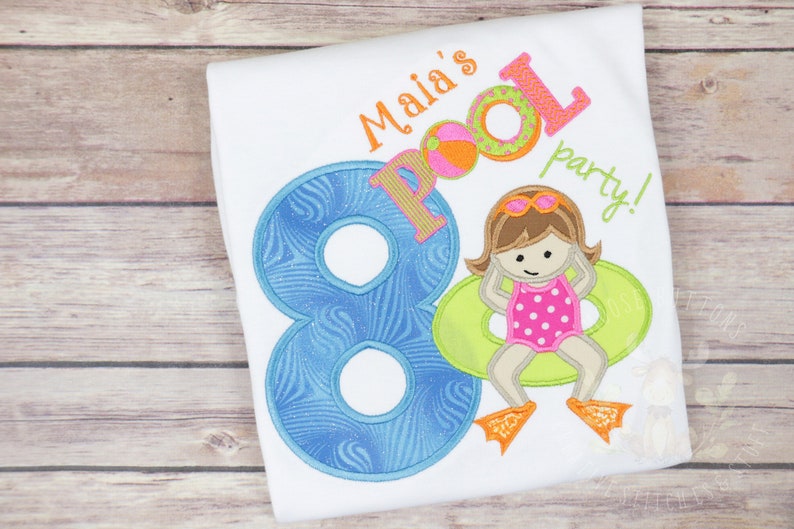 May include: A white t-shirt with blue, green and orange embroidery. The embroidery includes the number 8, the words "Malia's Pool Party!" and a cartoon girl wearing a pink swimsuit and a green float.