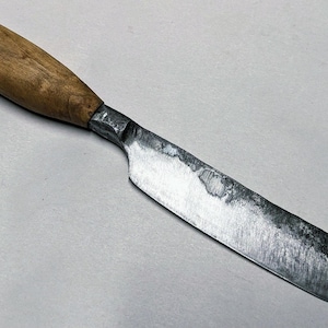 以下が含まれることがあります： 木製の柄と銀色の刃が付いた手作りのナイフ。柄は明るい茶色で、刃はわずかに湾曲した形状をしています。ナイフは金属製で、切ったりスライスしたりするために使用される可能性があります。刃の長さは約15cmです。