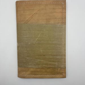 May include: A brown leather wallet with a stitched seam and a light brown and green fabric panel.