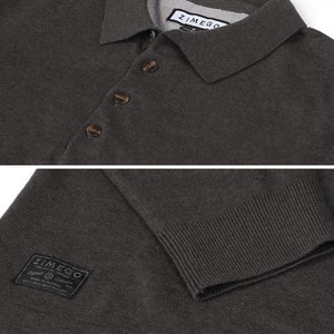 May include: A dark gray knitted polo shirt with a button-up collar and short sleeves. The shirt has a small black patch with the text "ZIMMER" on the left side of the chest.