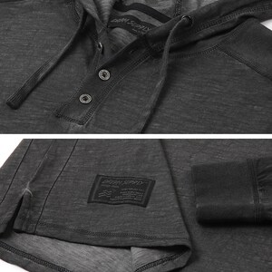 May include: A charcoal gray long-sleeve hooded shirt with a button placket and a small black label with the text "DRK SUPPLY" on the front. The shirt has a relaxed fit and a distressed look.