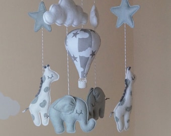 Móvil para bebé monocromático con jirafa, elefante, estrellas, nubes y globo aerostático.