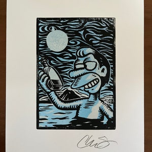 May include: A black and white linocut print of a cartoon character holding a bottle. The character has a blue and white body and is set against a blue and black background with a white moon.