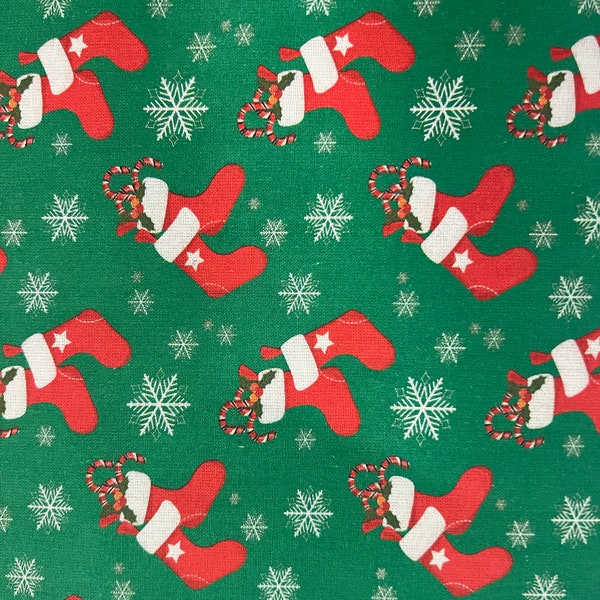 Christmas theme cotton quilting fabric green background with bright red Christmas stockings with candy canes.